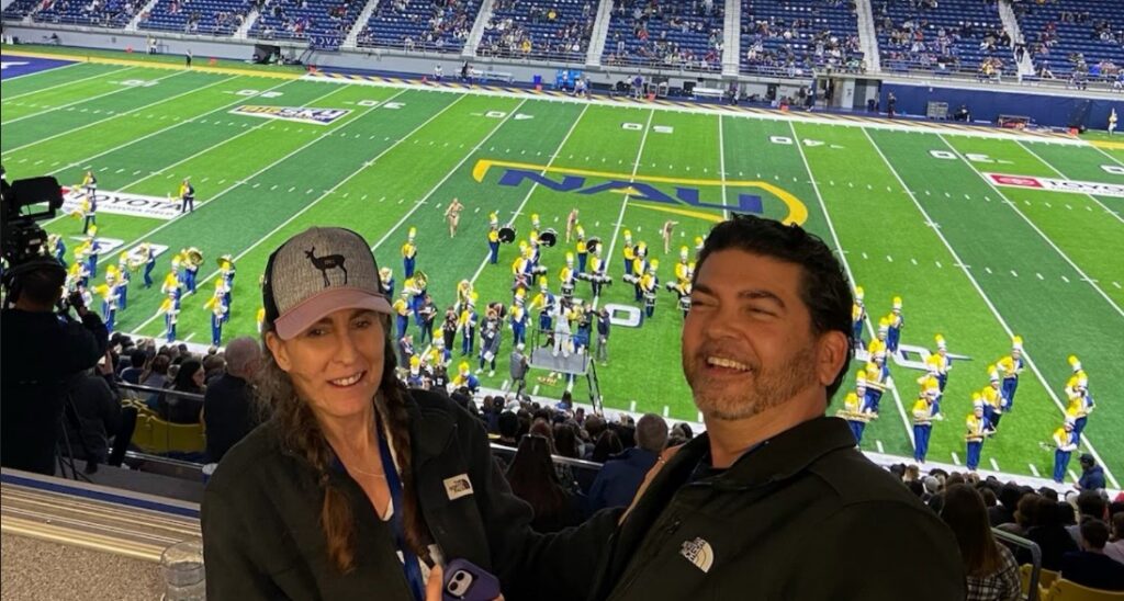 Melissa and Armando Bernasconi watching Quality Connections members performing with the NAU marching band.