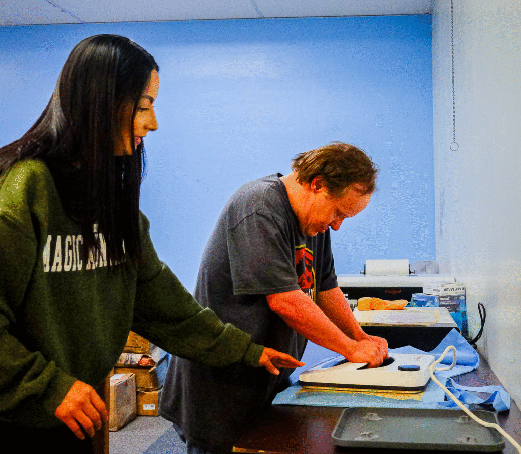Amy King helping a member of the Pathways program apply a graphic transfer to cloth